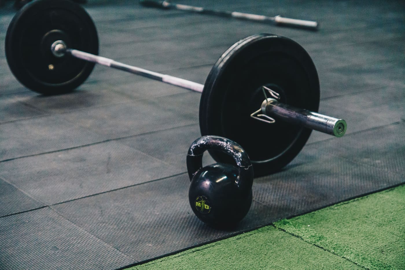Barra carregada e kettlebell no piso da área funcional